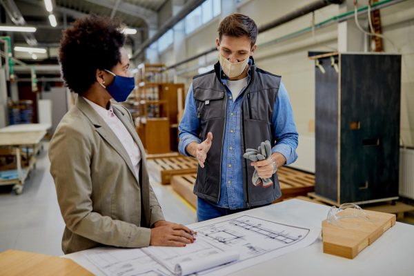 male-carpenter-explaining-design-plans-african-american-female-manager-production-facility